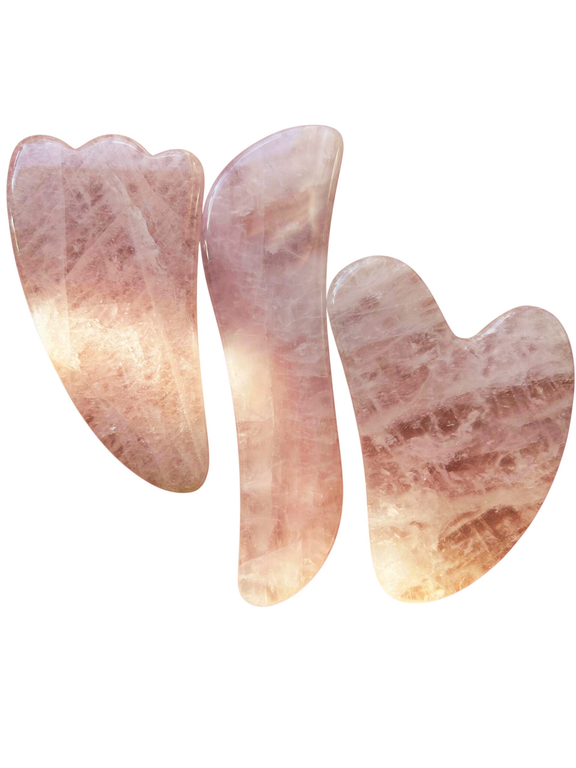Three pink rose quartz shapes resembling fingers arranged on a white background, abstract sculpture-like composition.